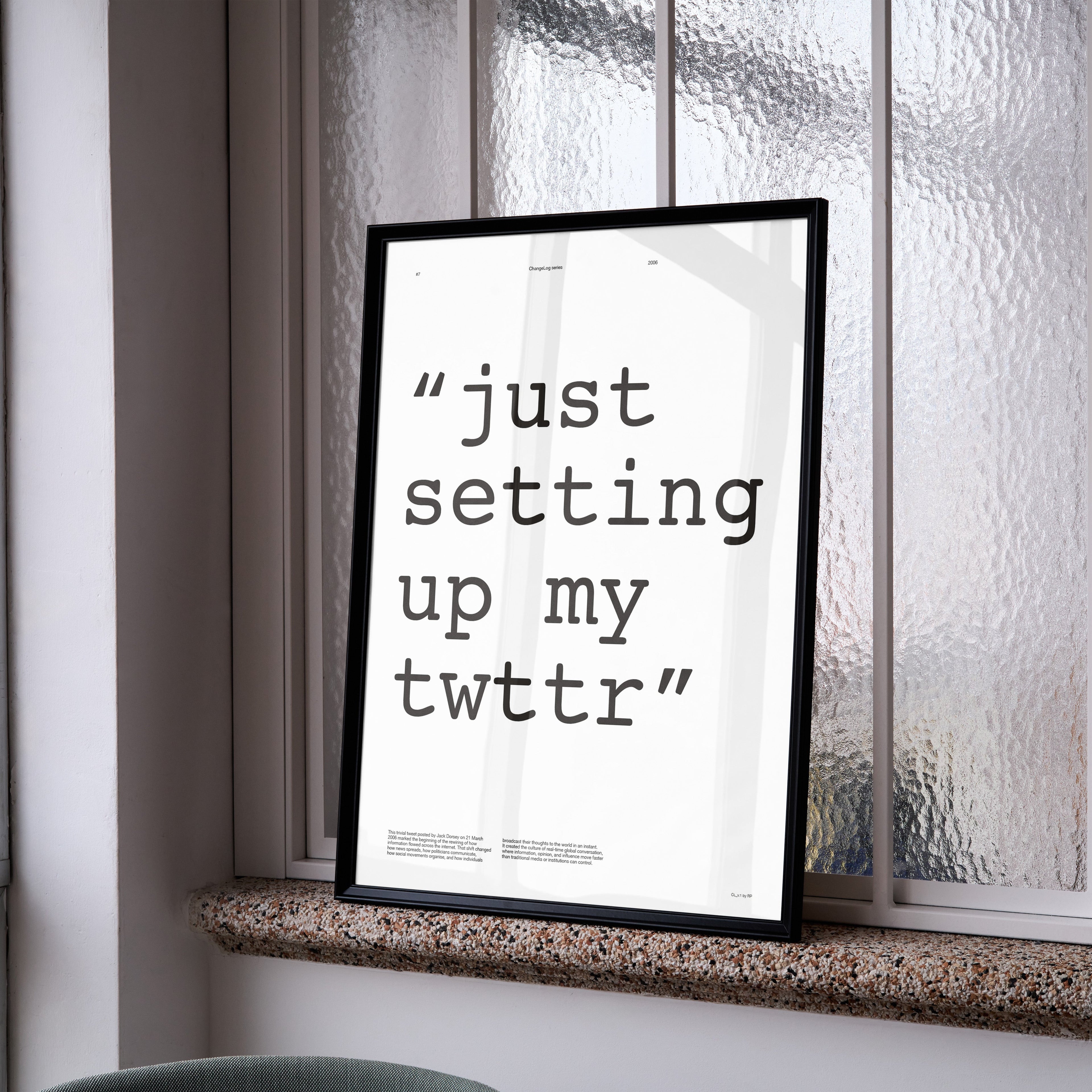 Framed poster with text 'just setting up my twttr' on a window sill.